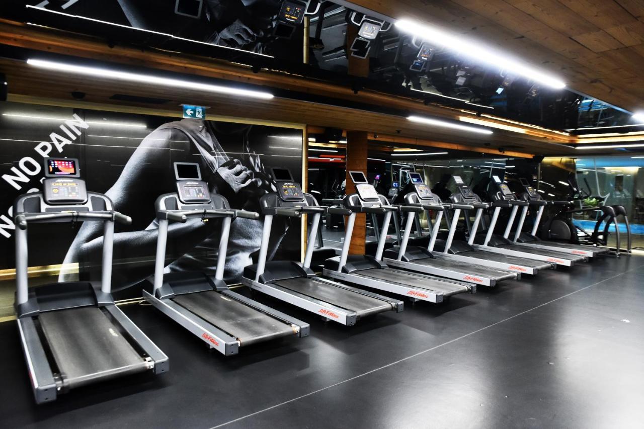 Dosso Dossi Hotels & Spa Downtown Estambul Exterior foto The photo shows a row of treadmills in a gym setting. The treadmills are modern and aligned next to each other on a sleek black floor. The background features a large image of a runner's foot, with motivational phrases that suggest themes of fitness 