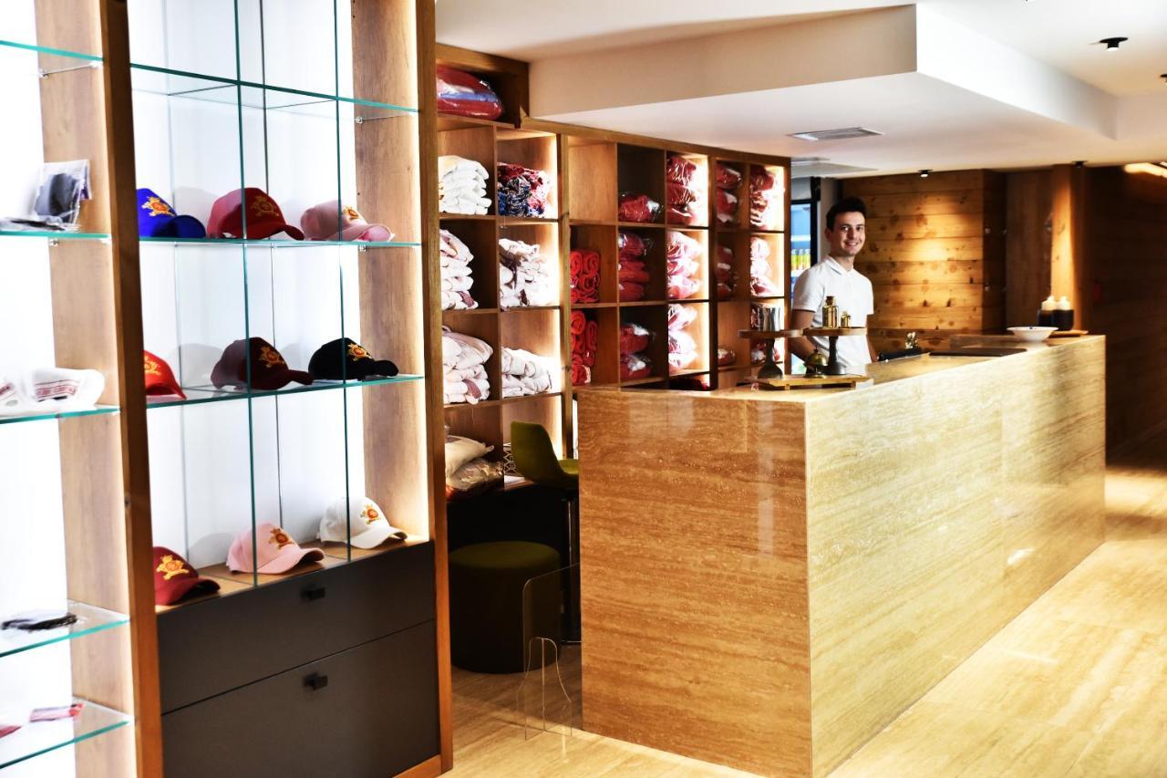 Dosso Dossi Hotels & Spa Downtown Estambul Exterior foto The photo shows a retail space or reception area with a warm and modern design. On the left, there are shelves displaying various colorful caps, neatly arranged behind glass. The right side features a wooden counter where a staff member is standing, 