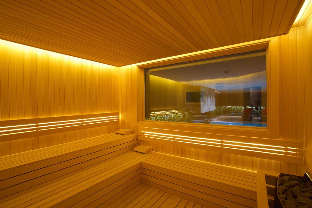 Dosso Dossi Hotels & Spa Downtown Estambul Exterior foto The photo depicts a sauna interior characterized by wooden paneling and warm, ambient lighting. The walls and seating are made of light-colored wood, creating a cozy atmosphere. There is a large window that offers a view into another room, possibly f