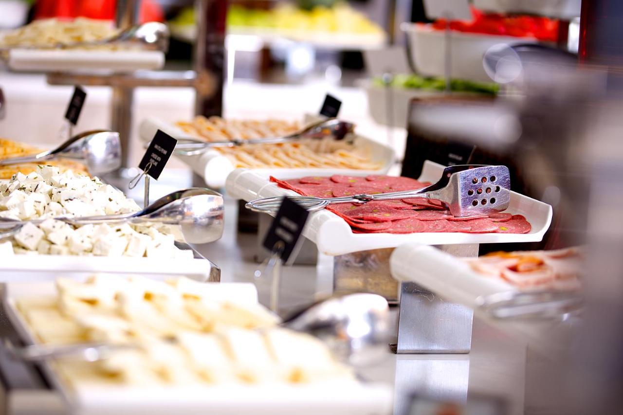 Dosso Dossi Hotels & Spa Downtown Estambul Exterior foto The image displays a buffet setting with various food items arranged on tables. There are multiple white serving trays filled with different types of food, including sliced meats, spreads, and possibly salads or other accompaniments. Each tray has a 