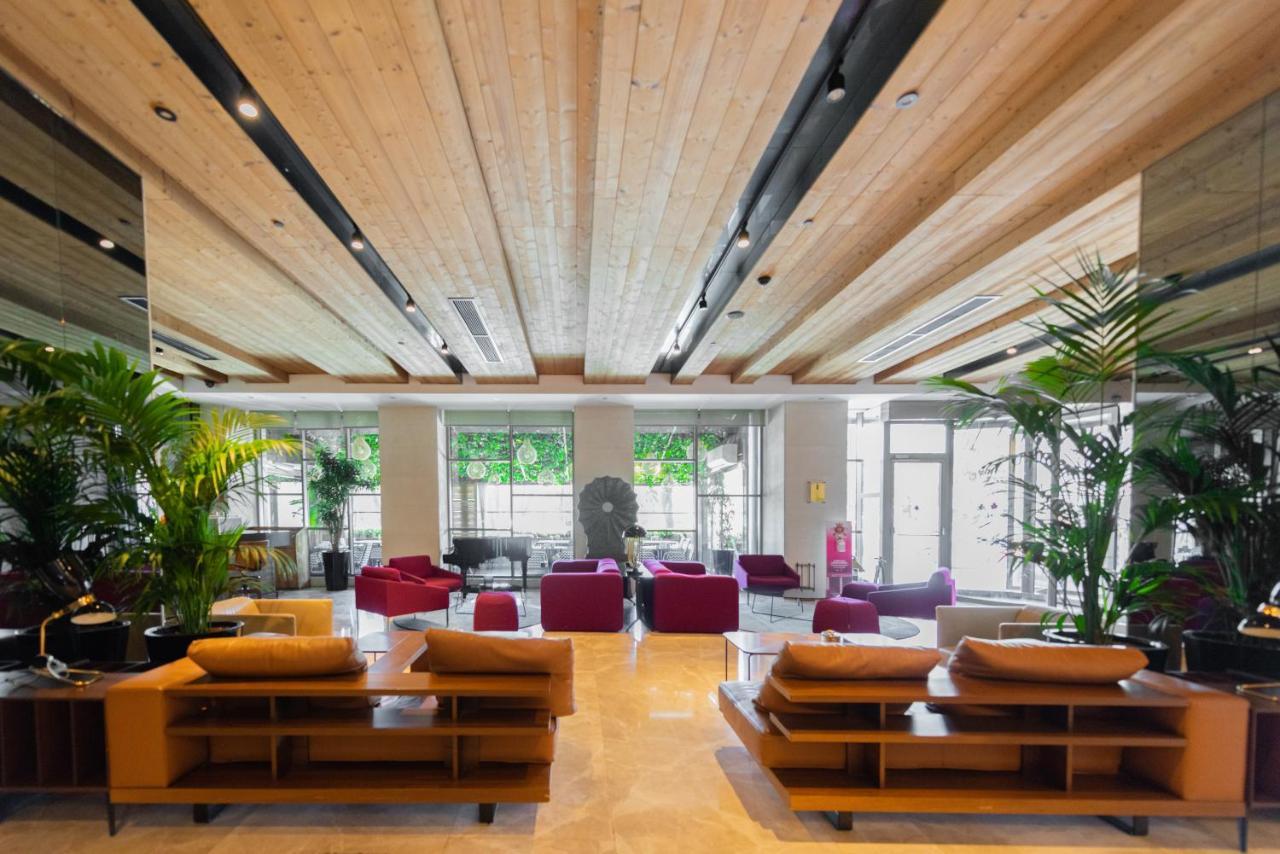 Dosso Dossi Hotels & Spa Downtown Estambul Exterior foto The photo shows a modern and spacious lobby area. There are wooden beams on the ceiling, giving the space a warm and inviting atmosphere. The flooring appears to be light-colored stone or tile. 

In the center of the room, there are several seating a
