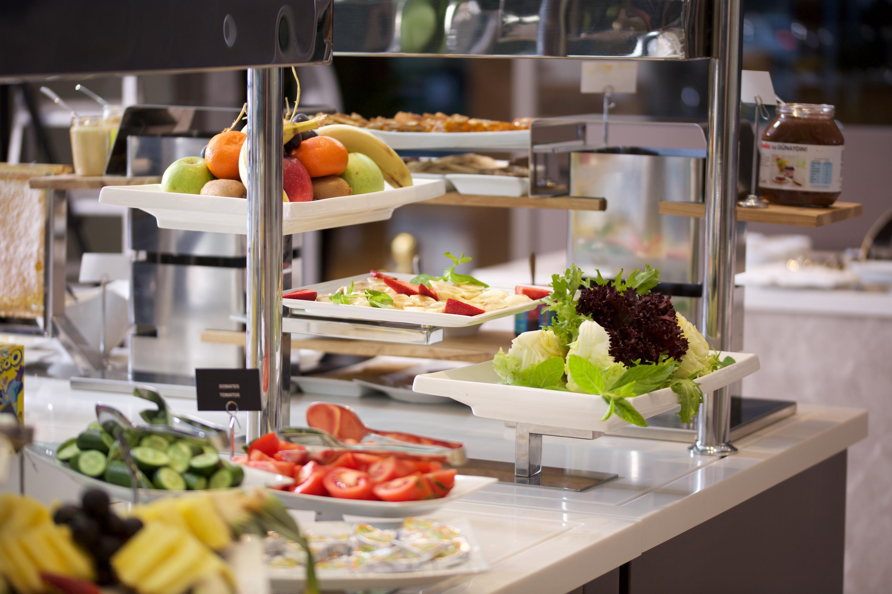 Dosso Dossi Hotels & Spa Downtown Estambul Exterior foto The photo depicts a buffet-style setup featuring a variety of fresh food items. There are several trays with colorful fruits, including apples and bananas, positioned on one side. In front, there are plates with vegetables, like sliced tomatoes and l