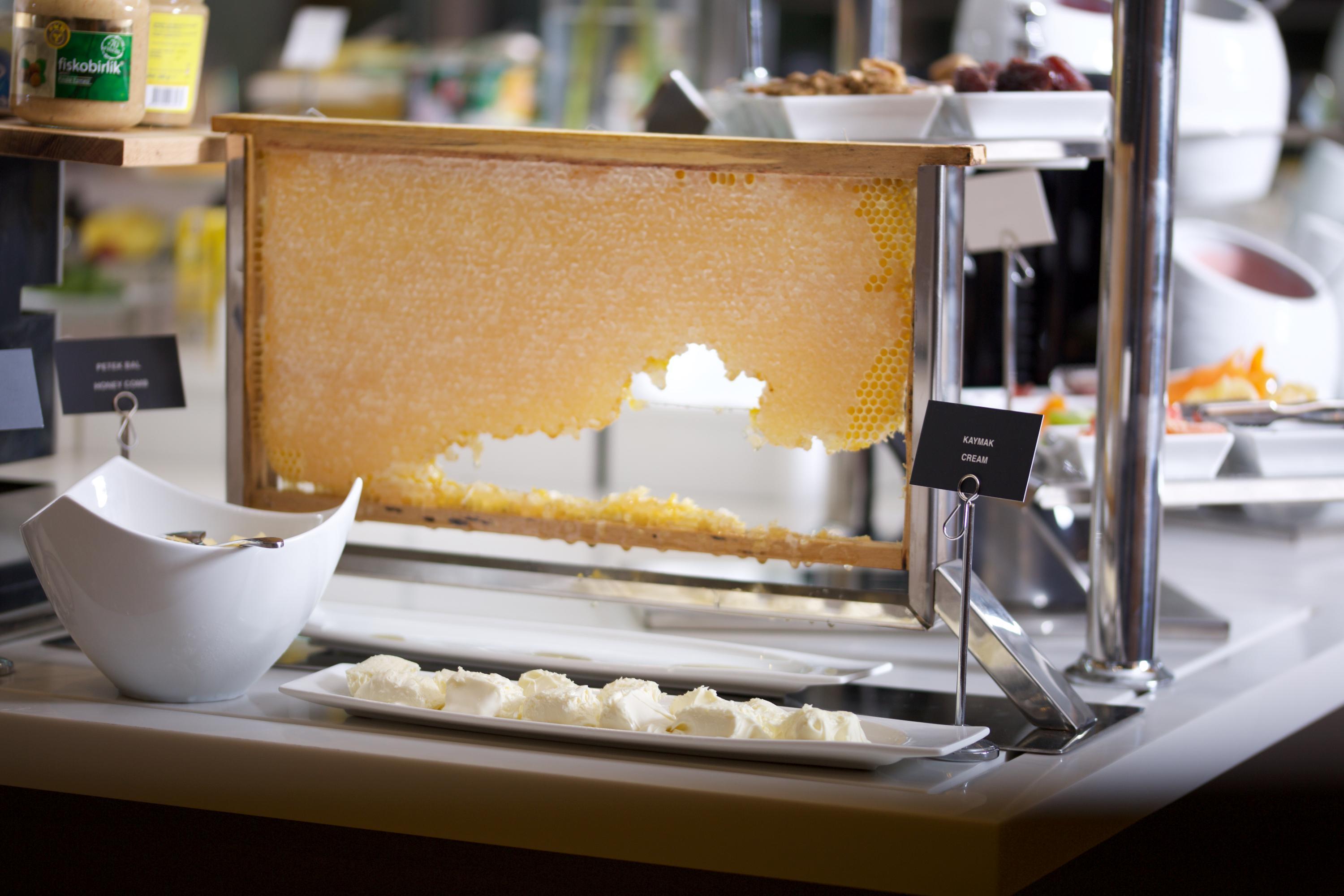 Dosso Dossi Hotels & Spa Downtown Estambul Exterior foto The photo shows a buffet setup featuring a large piece of honeycomb displayed in a frame, from which honey can be extracted. Below the honeycomb, there is a white dish containing small portions of what appears to be a creamy substance, likely a dairy
