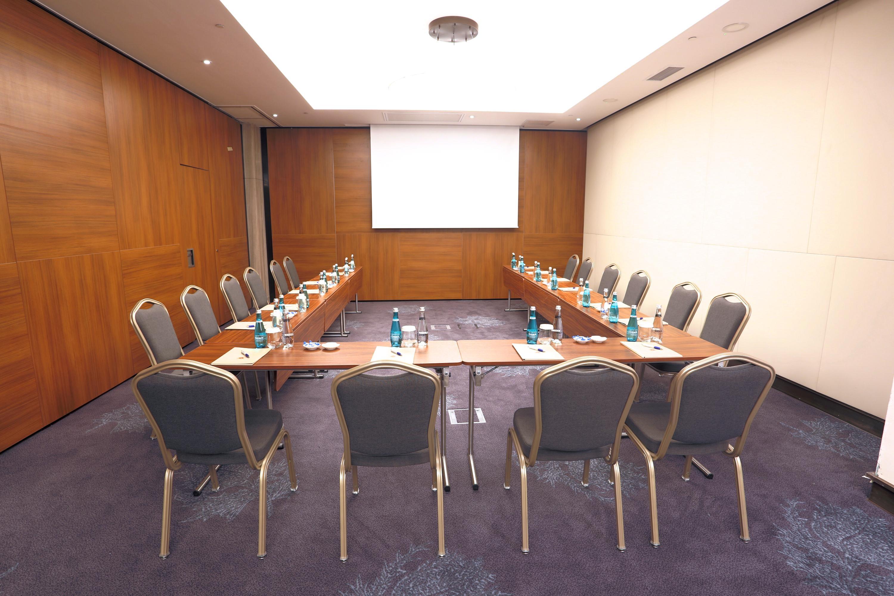 Dosso Dossi Hotels & Spa Downtown Estambul Exterior foto The photo shows a conference room setup. There are several rectangular tables arranged in a U-shape, surrounded by chairs. Each table has a water bottle and a notepad placed on it, suggesting it's intended for a meeting or presentation. The walls are