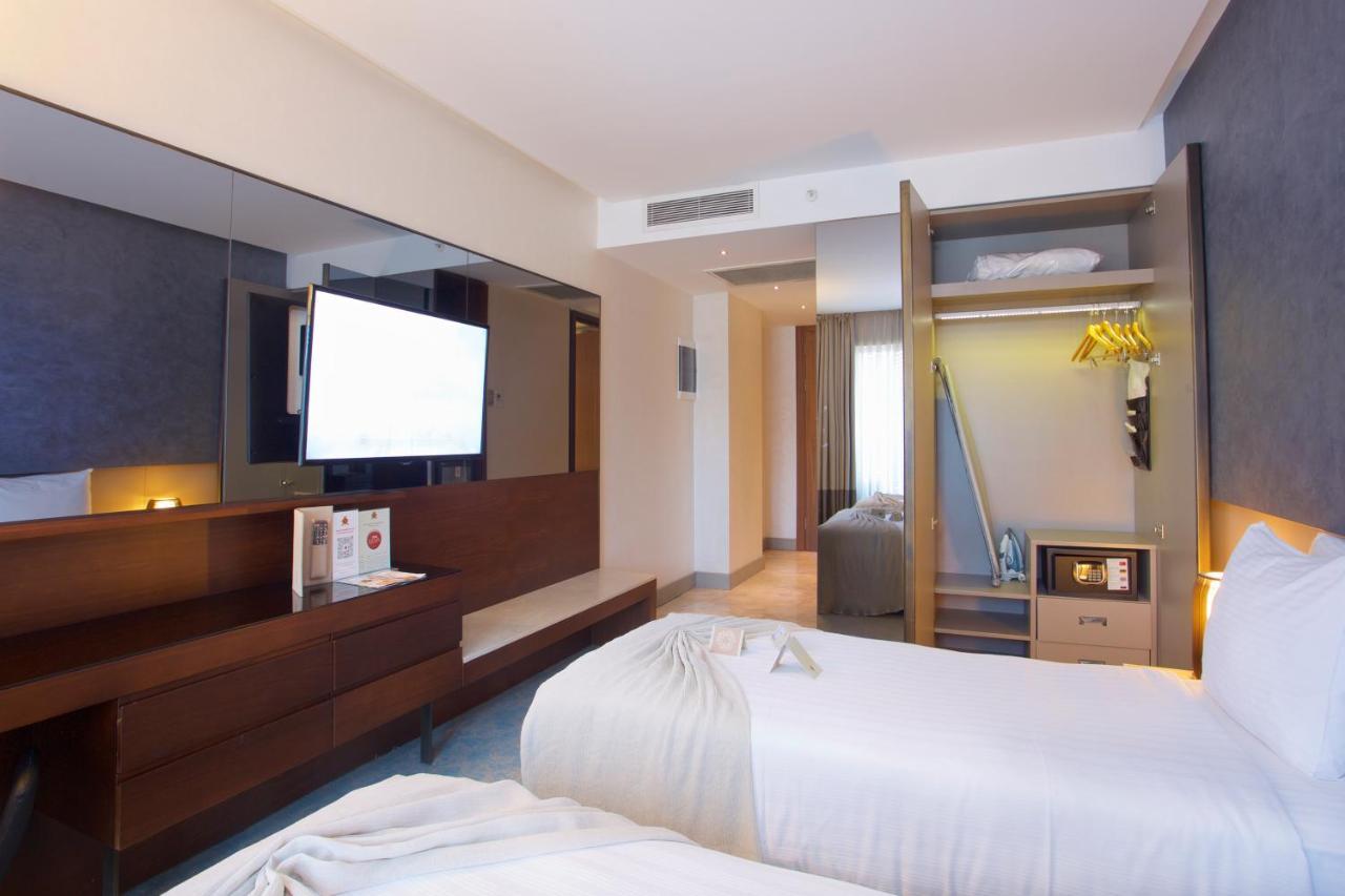 Dosso Dossi Hotels & Spa Downtown Estambul Exterior foto The photo shows a modern hotel room featuring two separate beds with white bedding. There's a large flat-screen TV mounted on the wall opposite the beds, and a stylish wooden cabinet beneath it. One corner of the room has an open closet with hanging 