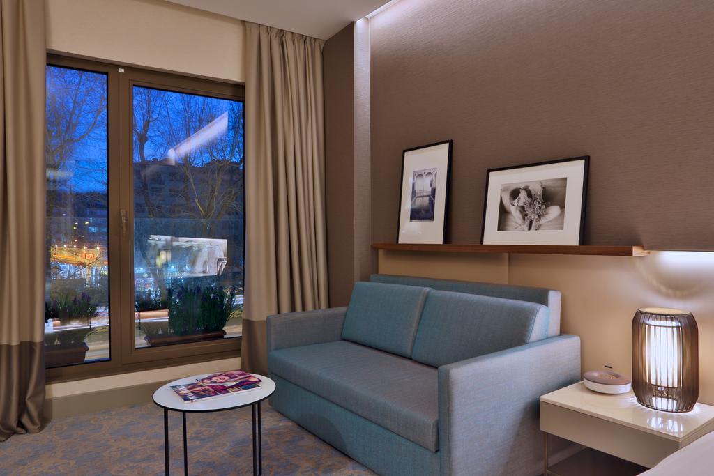 Dosso Dossi Hotels & Spa Downtown Estambul Exterior foto The photo shows a modern and cozy interior of a room. There is a light blue sofa positioned against a wall, accompanied by a round coffee table with a magazine on top. Two black-and-white framed photographs are hanging on the wall above the sofa. Lar