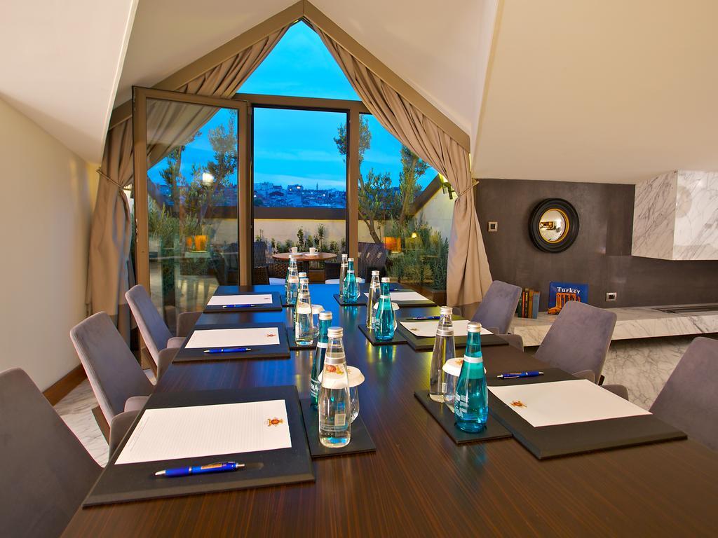 Dosso Dossi Hotels & Spa Downtown Estambul Exterior foto The photo shows a conference room setup. There is a long wooden table with several chairs arranged around it. On the table, there are notebooks or notepads, pens, and bottles of water, all placed neatly. The room features large windows with curtains,