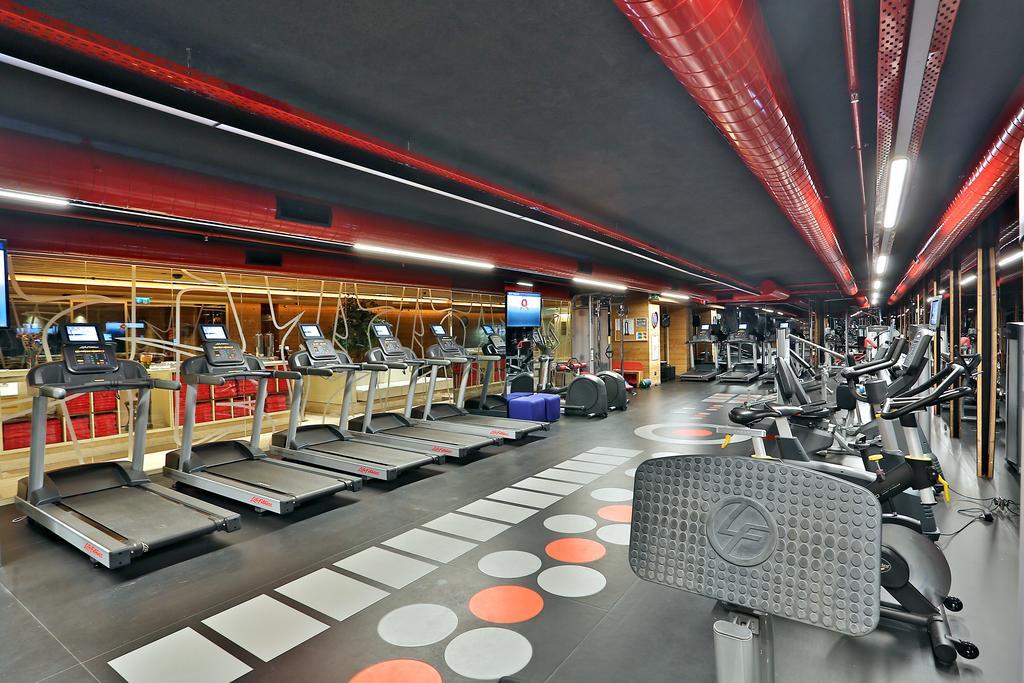 Dosso Dossi Hotels & Spa Downtown Estambul Exterior foto The photo shows a modern fitness gym featuring various exercise equipment. On one side, there are several treadmills lined up, facing a screen, likely for entertainment or workout tracking. The flooring has a unique design with colorful circles, and 