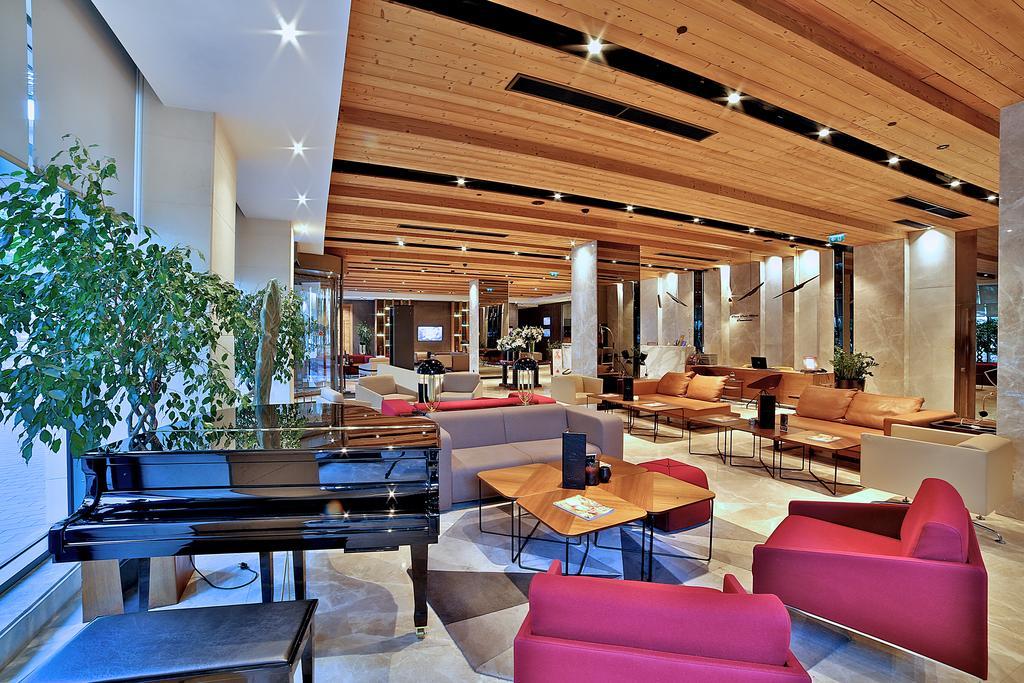 Dosso Dossi Hotels & Spa Downtown Estambul Exterior foto The image shows a spacious and modern lobby area of a building, likely a hotel or an upscale public space. The interior features a high wooden ceiling with ambient lighting, giving it a warm and inviting atmosphere. 

In the foreground, there is a gr