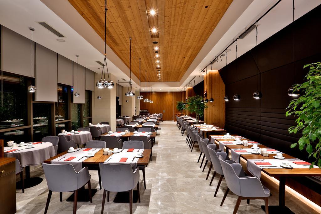 Dosso Dossi Hotels & Spa Downtown Estambul Exterior foto The photo depicts a modern restaurant interior. The space features a combination of wooden and polished surfaces, with a prominent wooden ceiling. 

Tables are set with white tablecloths and neatly arranged dishware, indicating a refined dining exper